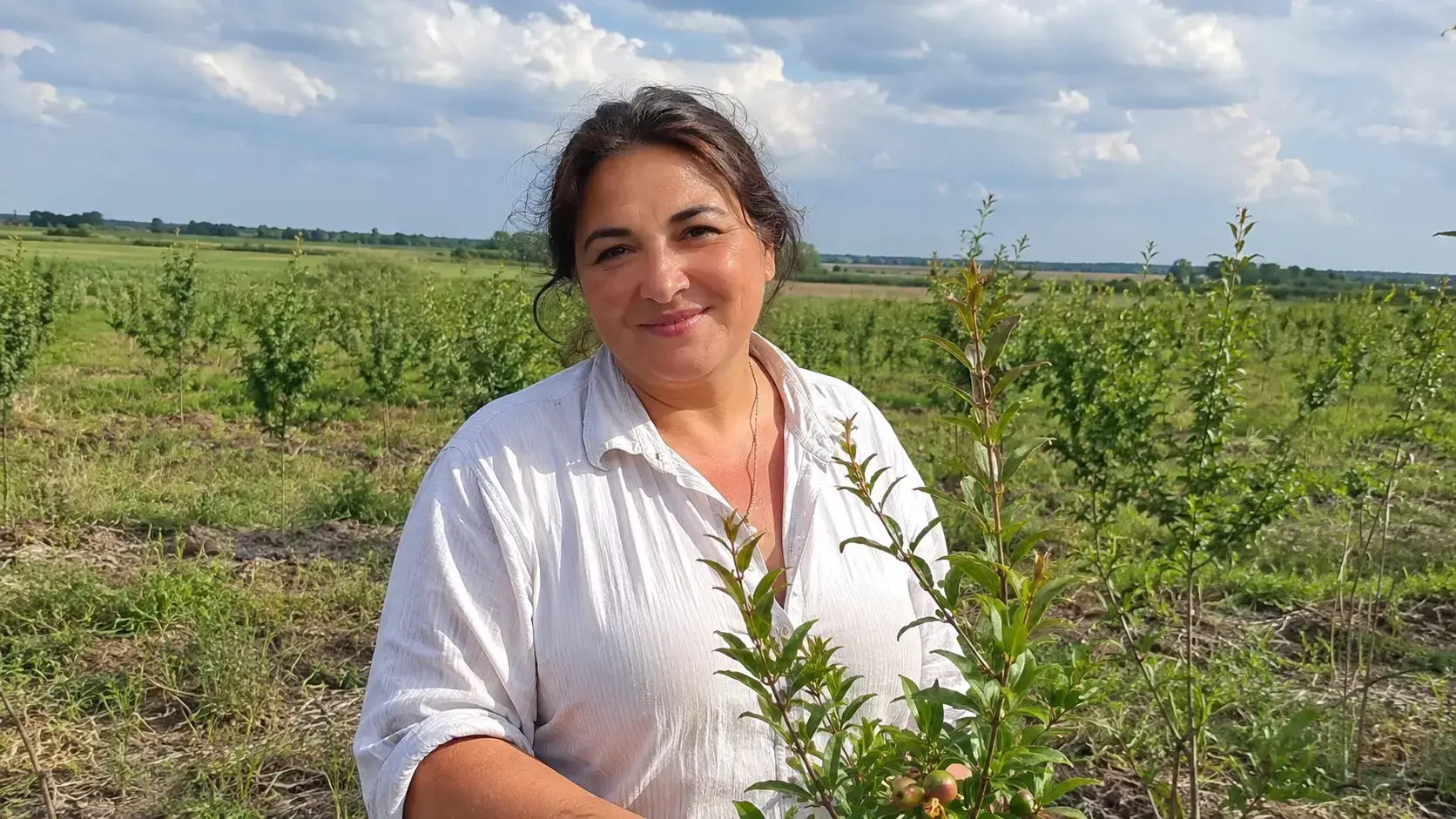 Фото: портрет Наталії Алієвої на фоні молодого гранатового саду, тепла усмішка